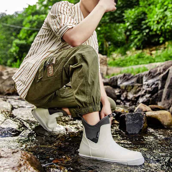 Model draagt Elin regenlaarzen bij het aantrekken op rotsen