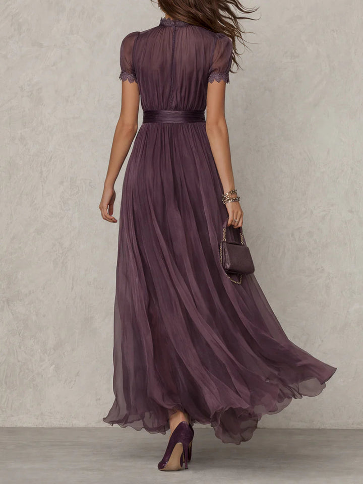 Back view of purple maxi dress with sheer short sleeves, fitted waist, and floor-length chiffon