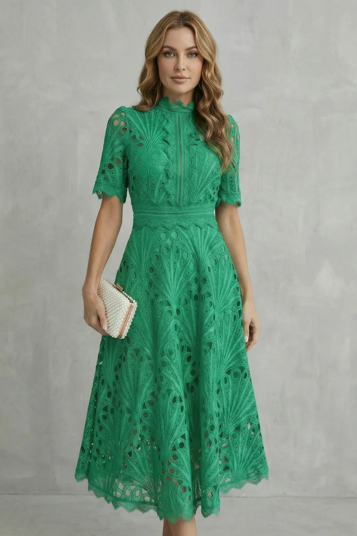 Green lace midi dress with high neck, short sleeves, and scalloped hem, styled with a pearl clutch