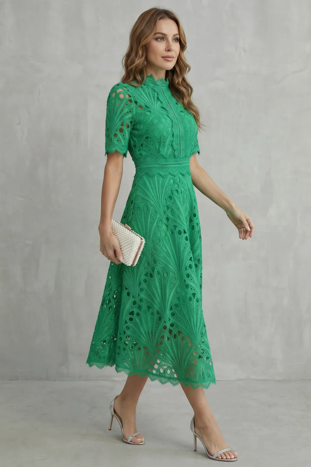 Side view of green wedding guest lace midi dress with high neck and fitted waist, worn with silver heels