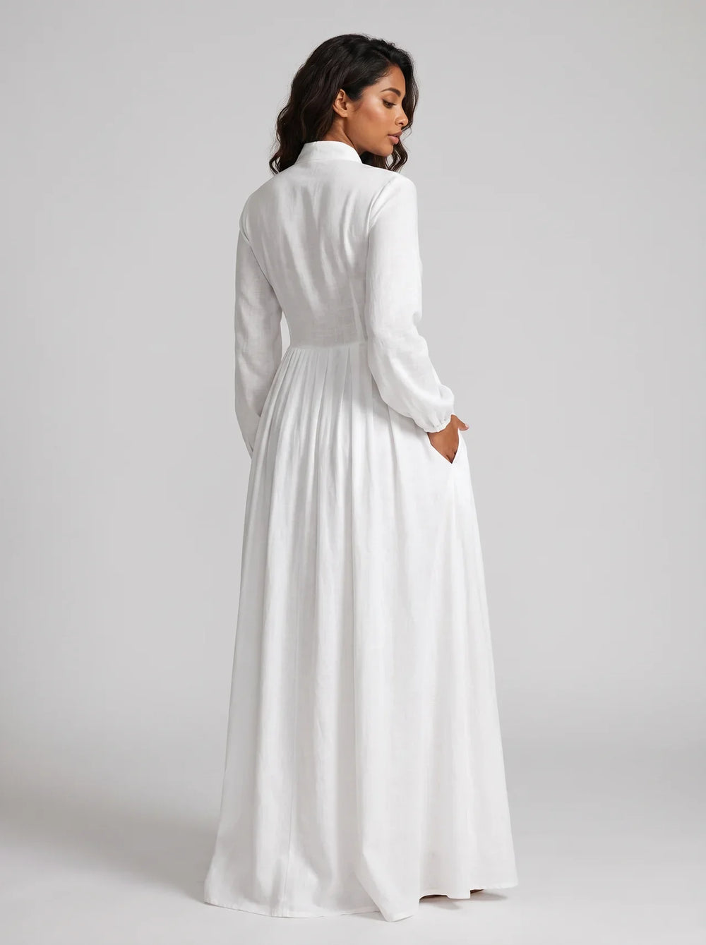 Woman wearing a long white dress against a plain background