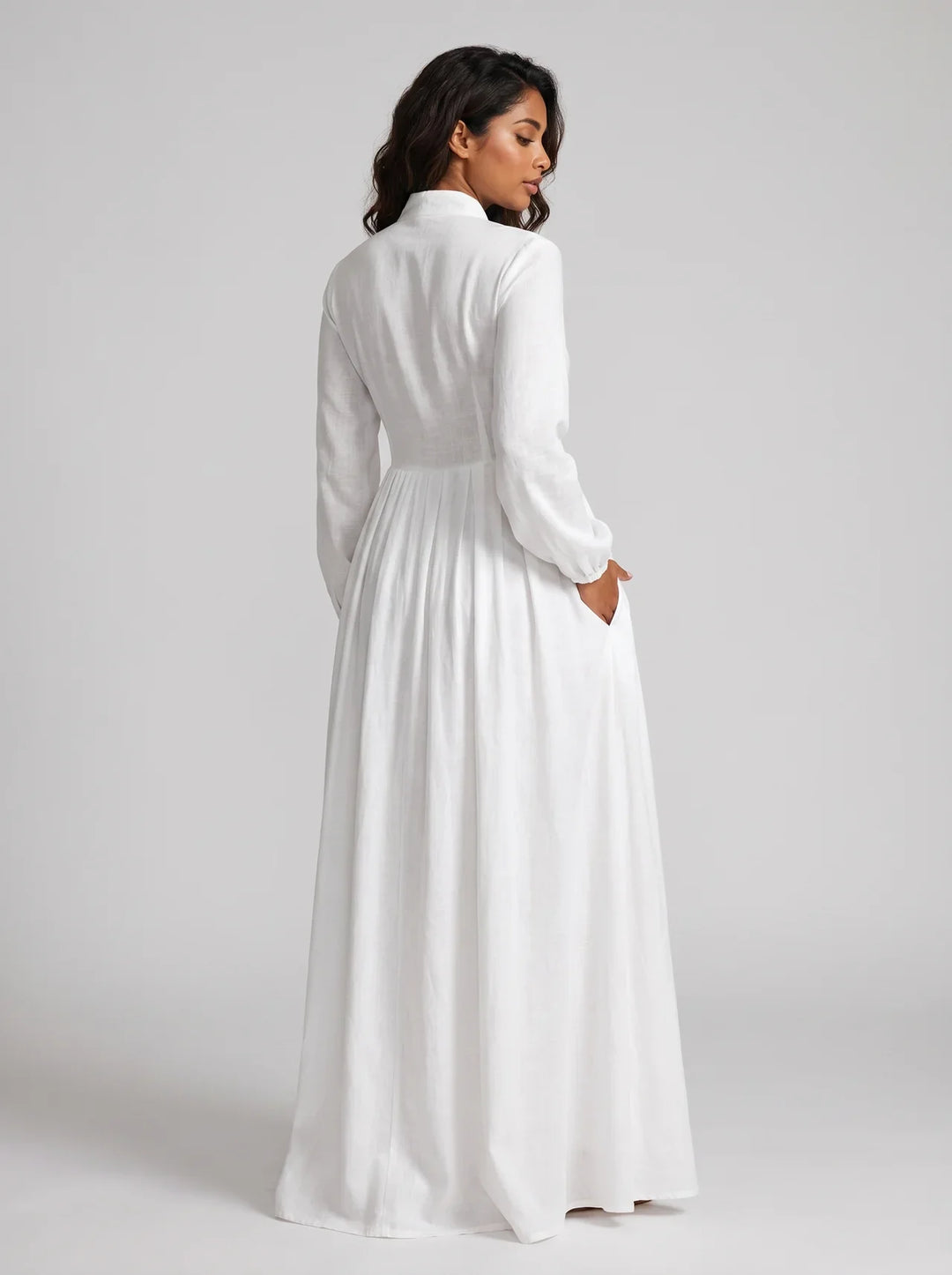 Woman wearing a long white dress against a plain background