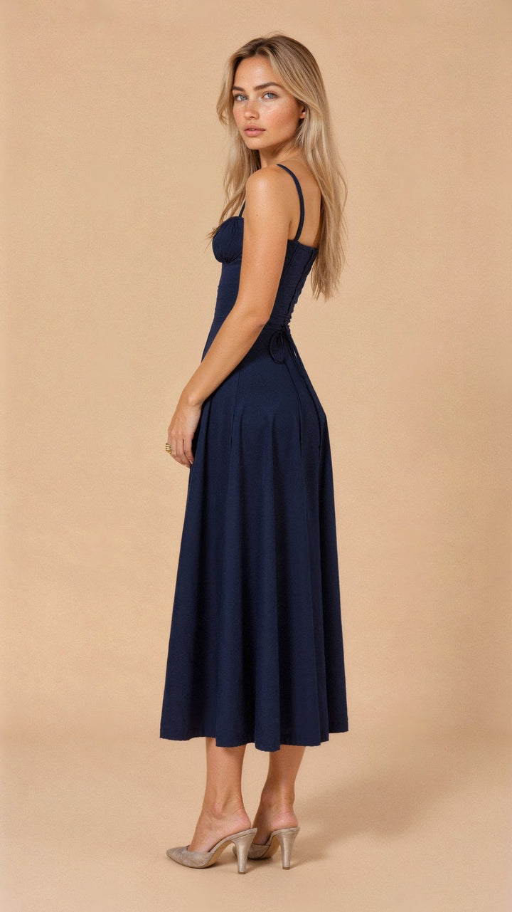 Side view of a navy blue summer midi dress, showing the lace-up back and flowing skirt.