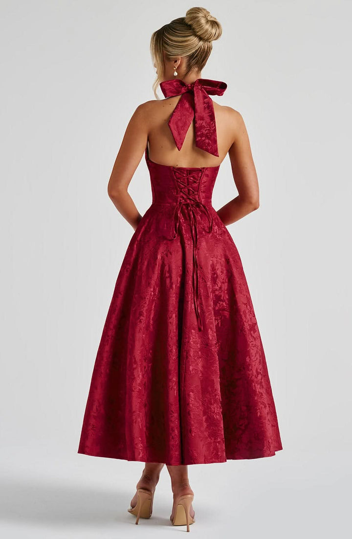 Back view of burgundy velvet halter dress with bow and lace-up