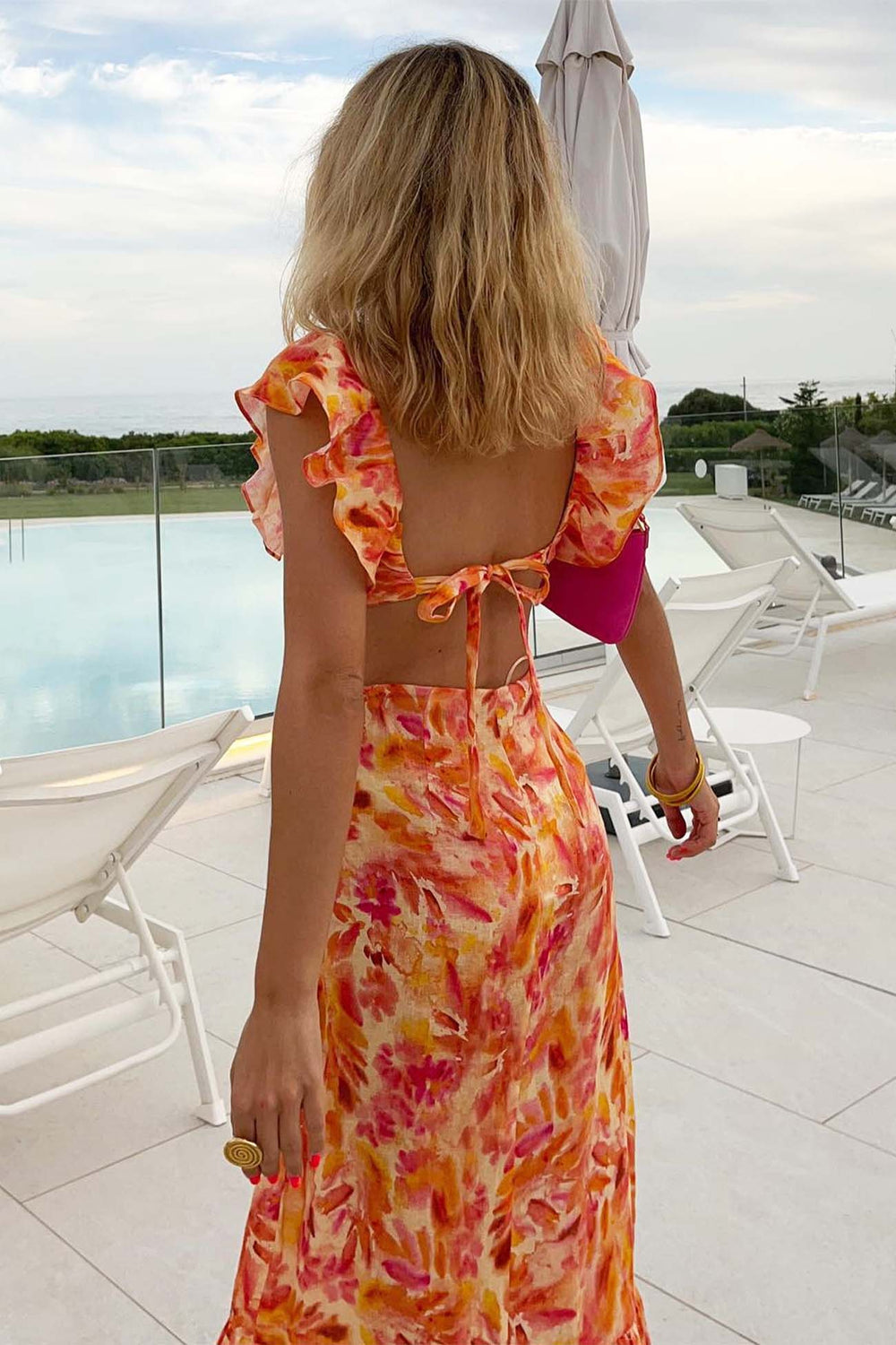 Back view of orange floral V neck maxi dress with open back tie and flutter sleeves